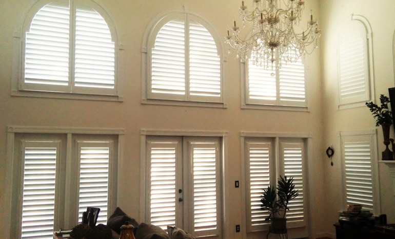 Great room in open concept Philadelphia home with plantation shutters on arch windows.