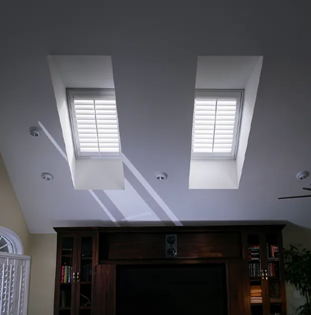 White Polywood shutters on two skylight windows above in a high ceiling
