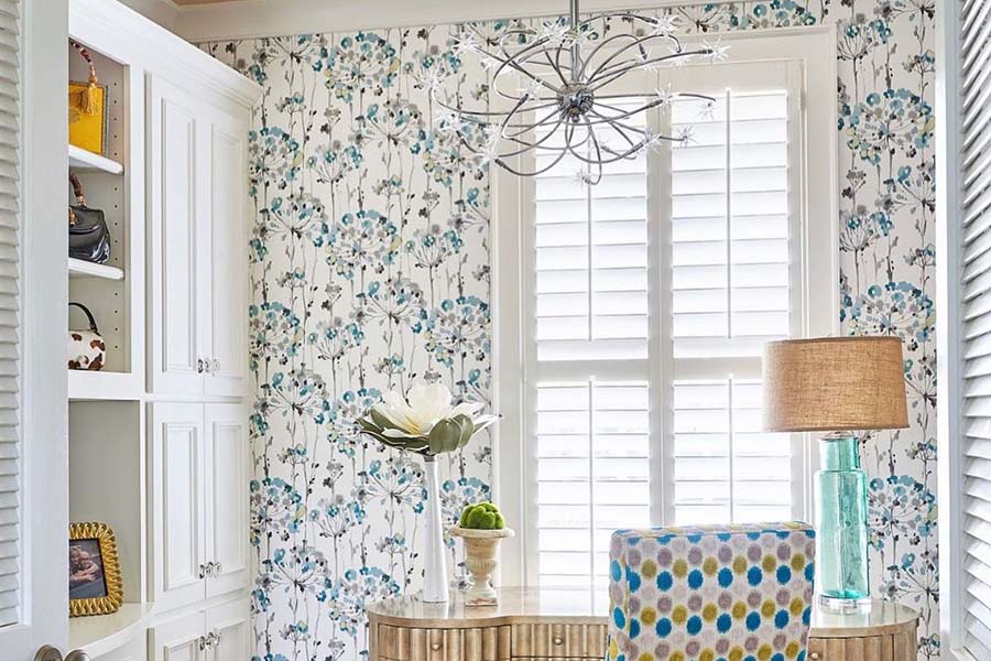 Interior shutters bringing light into a dressing area with small table and chair