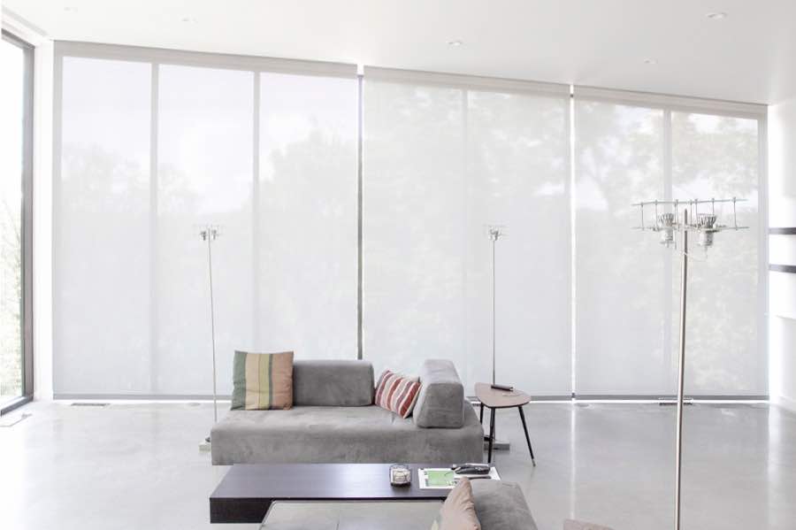 Motorized window shades make controlling natural light effortless in your Philadelphia great room. White motorized shades on a wall of tall great room windows