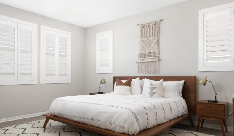 Polywood shutters are popular in Northeast homes because they can resist damage from extreme temperatures. Polywood shutters in a bedroom.