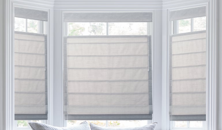 Roman shades are made of a thick material which keeps cold air out.  Roman shades in a bay window.