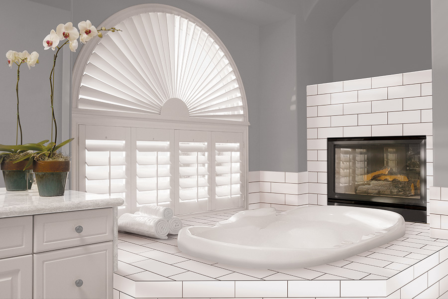 Explore our selection of window treatments for builders in Philadelphia to find the perfect ones for your next construction project. White Polywood shutters on an arched bathroom window