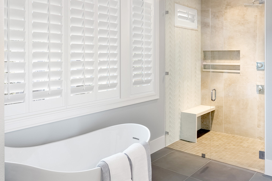 Awnings are perfect for wide Polywood shutter windows. White large Polywood shutters in a modern bathroom.