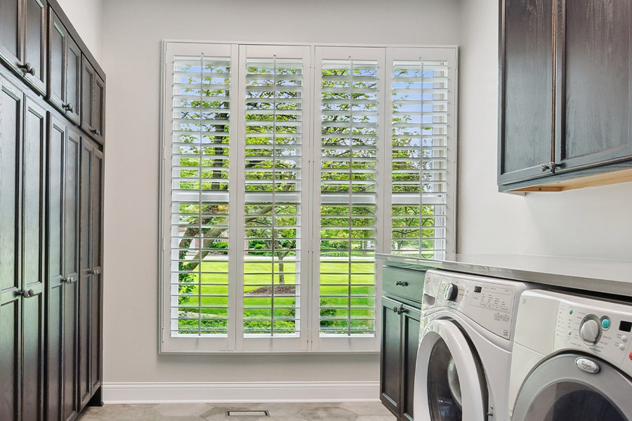 Find the perfect level of natural light for your Philadelphia laundry room with interior shutters. White Polywood shutters letting light through a laundry room window