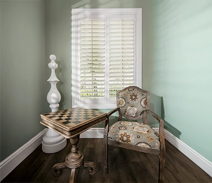 white polywood shutters in a small nook area with a table and chair along with a chess board and chess decor