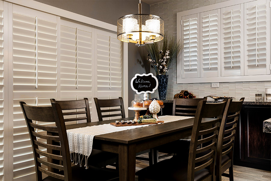 Polywood shutters blocks light and provide energy-efficiency Faux wood plantation shutters covering doors and windows within dining room